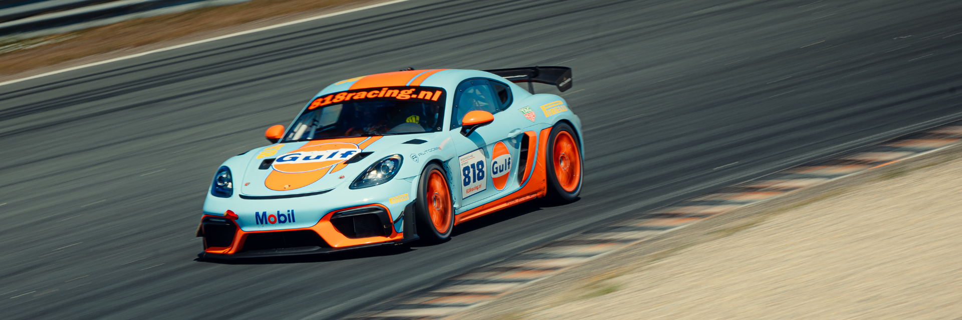 818 Racing Porsche in lichtblauw en oranje op het circuit
